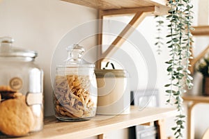 Grocery and kitchenware on the wooden shelves in modern bright kitchen