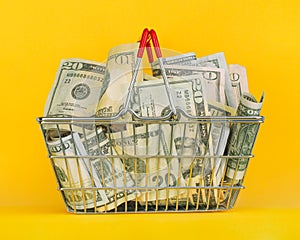 Grocery shopping basket full of money in dollar bills. Concept showing increased cost of living and increased cost of basic goods