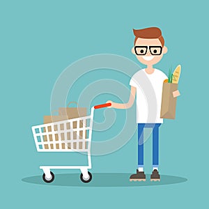 Grocery shopping concept: Young customer standing with a trolley