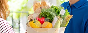 Grocery store delivery man delivering food to a woman customer at home, banner size