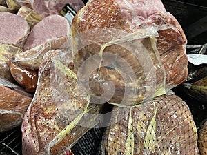 Grocery store whole hams on display pile