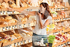 Grocery store: Young woman holding mobile phone