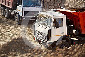 GRODNO, BELARUS - APRIL 2020: Two heavy laden multi-ton trucks MAZ exporting minerals from open-pit mine. Concept of