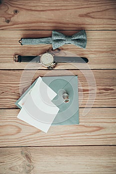 Groom accessories for wedding day â€“ watch, bow tie, rings, envelope with copy space card