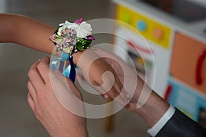 Groom attaches a small bracelet of flowers to the arm of his daughter or witness