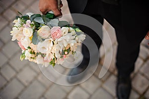 Groom in a black suit and classic shoes holding a wedding bouquet