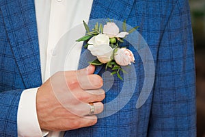 Groom in blue checkered suit with a white and pale pink rose bo