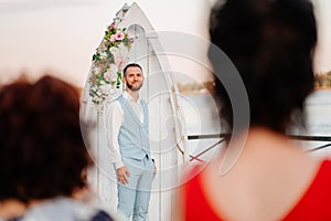 groom in blue suit is waiting for bride. wedding ceremony by water