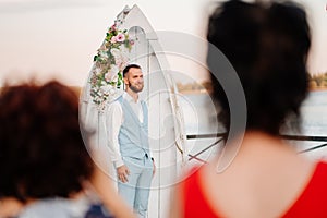 groom in blue suit is waiting for bride. wedding ceremony by water
