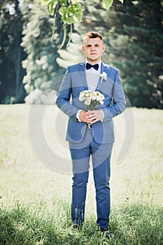 Groom with a bouquet of flowers in his hands waiting for the bride