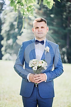 Groom with a bouquet of flowers in his hands waiting for the bride, close-up