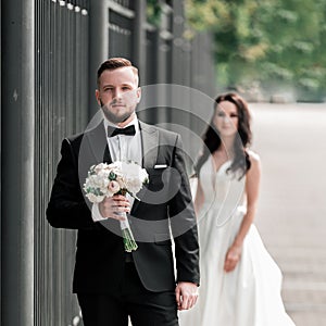 Groom with a bouquet of flowers waiting for his bride on the city street