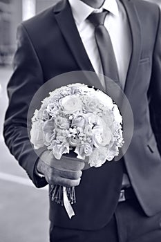 Groom and bouquet in hands close-up, dressing, man`s style, stylish man. Elegant young handsome man. Men`s jacket, hand cover th