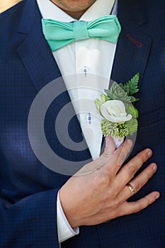 Groom boutonniere adjusts his hand in a jacket pocket