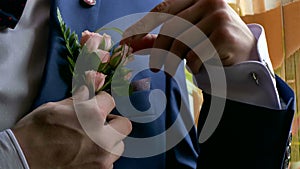 Groom boutonniere on man corrects his pocket hand