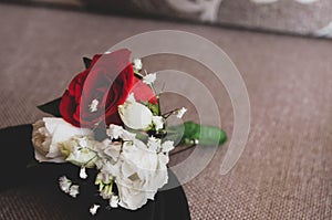 Groom boutonniere with red and white roses on black groom belt