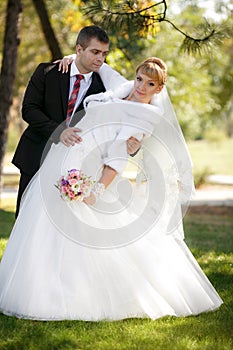 Groom and the bride in autumn park walk near trees with yellow leaves