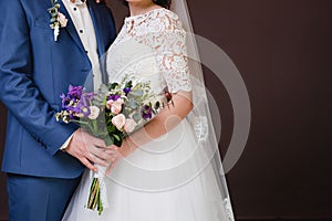 Groom with the bride, the bride`s bouquet, the bride is holding a bouquet, the bridegroom embraces the bride