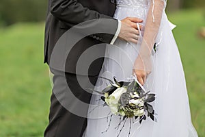 Groom with the bride, the bride`s bouquet, the bride is holding a bouquet, the bridegroom embraces the bride