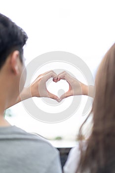 Groom and bride coordinate their hand together for create HEART shape with the clear sky