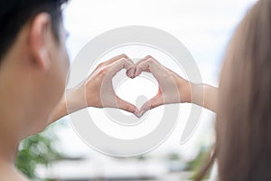 Groom and bride coordinate their hand together for create HEART shape with the clear sky