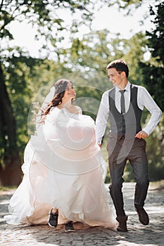 Groom and bride in the garden. Spring wedding in the park. Happy wedding couple running in the park. Stylish and beautiful.