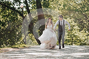 Groom and bride in the garden. Spring wedding in the park. Happy wedding couple running in the park. Stylish and beautiful.