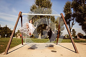 Groom and bride having fun on a swing set