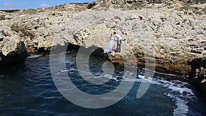 Groom bride jump off a cliff into the ocean