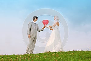 Groom and bride keep heart-shaped balloon