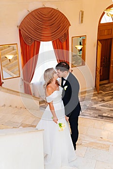 the groom and the bride kiss at the official wedding ceremony on the stairs