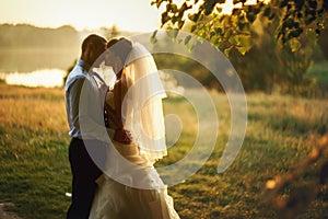 Groom and bride is kissing on the background lake and forest