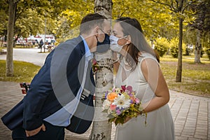 Groom and bride kissing each other in protective medical masks on face in