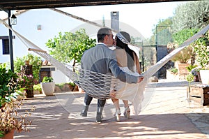 Groom bride kissing sitting in a hammock rope