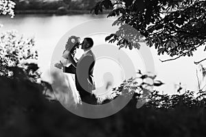 Groom and bride on the natire - a kiss behind a lake photo