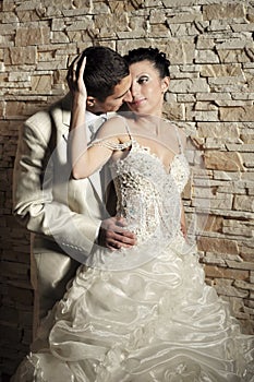 Groom and bride near the brick wall