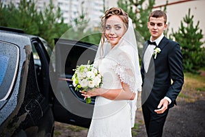 Groom and bride near wedding car