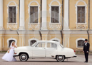 Groom and bride near white vintage car