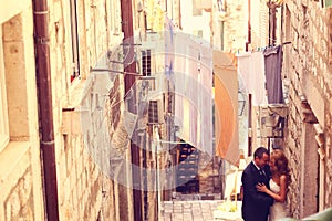 Groom and bride outdoors on a narrow street on their wedding day