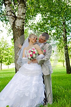 The groom and the bride in park near a tree