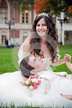 Groom and bride relaxing on a grass