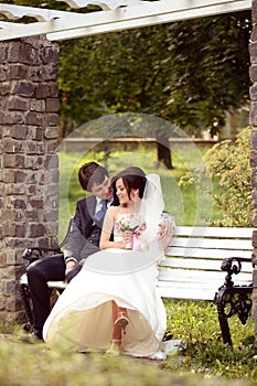 Groom and bride sitting on a bench