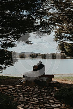 Groom and bride sitting on a bench on the lakeside