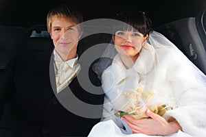 Groom and bride sitting inside limousine