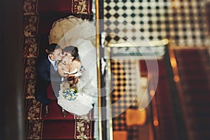 Groom and bride is sitting and kisssing on the stairs