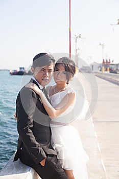 Groom and bride sitting on the sidewalk.