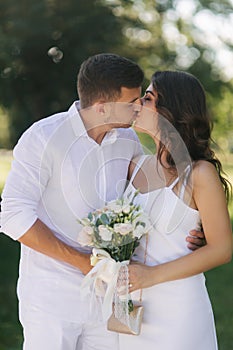 Groom and bride in their wedding day walking in the park. Newlyweds spend time together. Just married