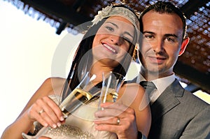 Groom and bride toasting smiling on a terrace looking ahead