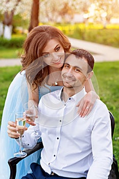 Groom and bride together, wedding couple. Young couple embracing, drinking champagne in blooming spring garden. Love and
