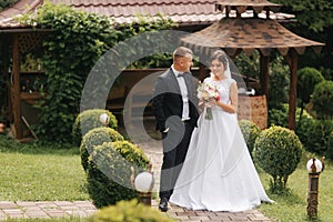 Groom and bride walk in the park on their wedding day. Happy couple spend time together